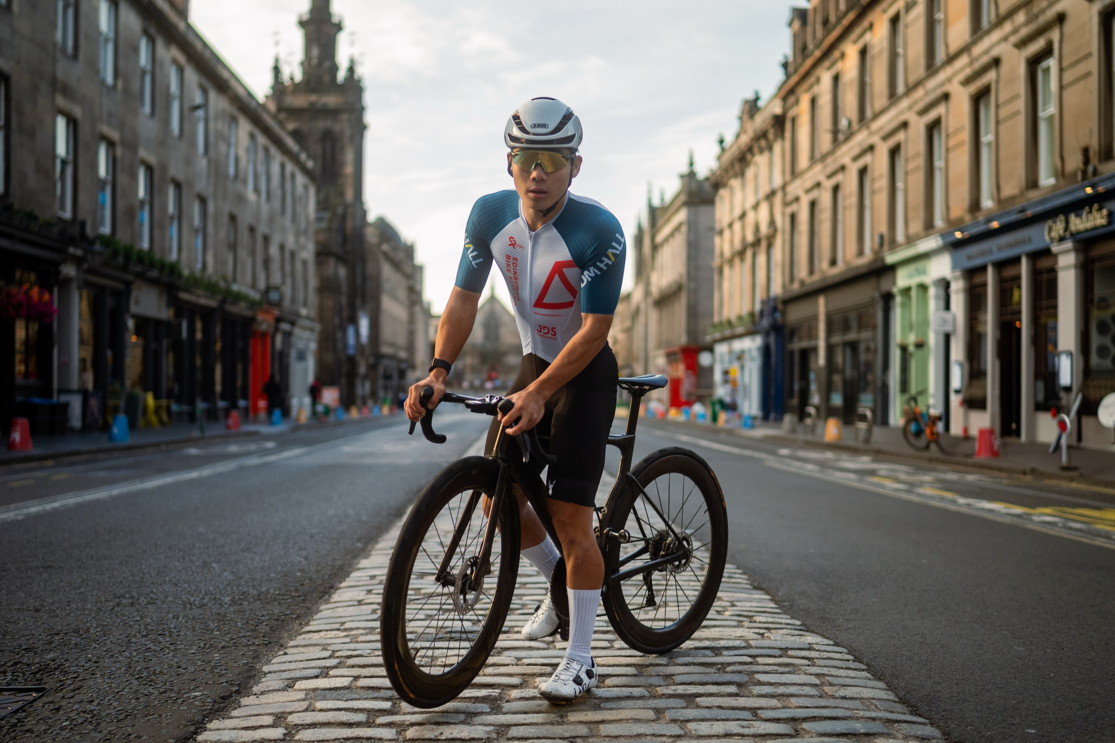 A cyclist riding toward the camera through Edinburgh's Royal Mile