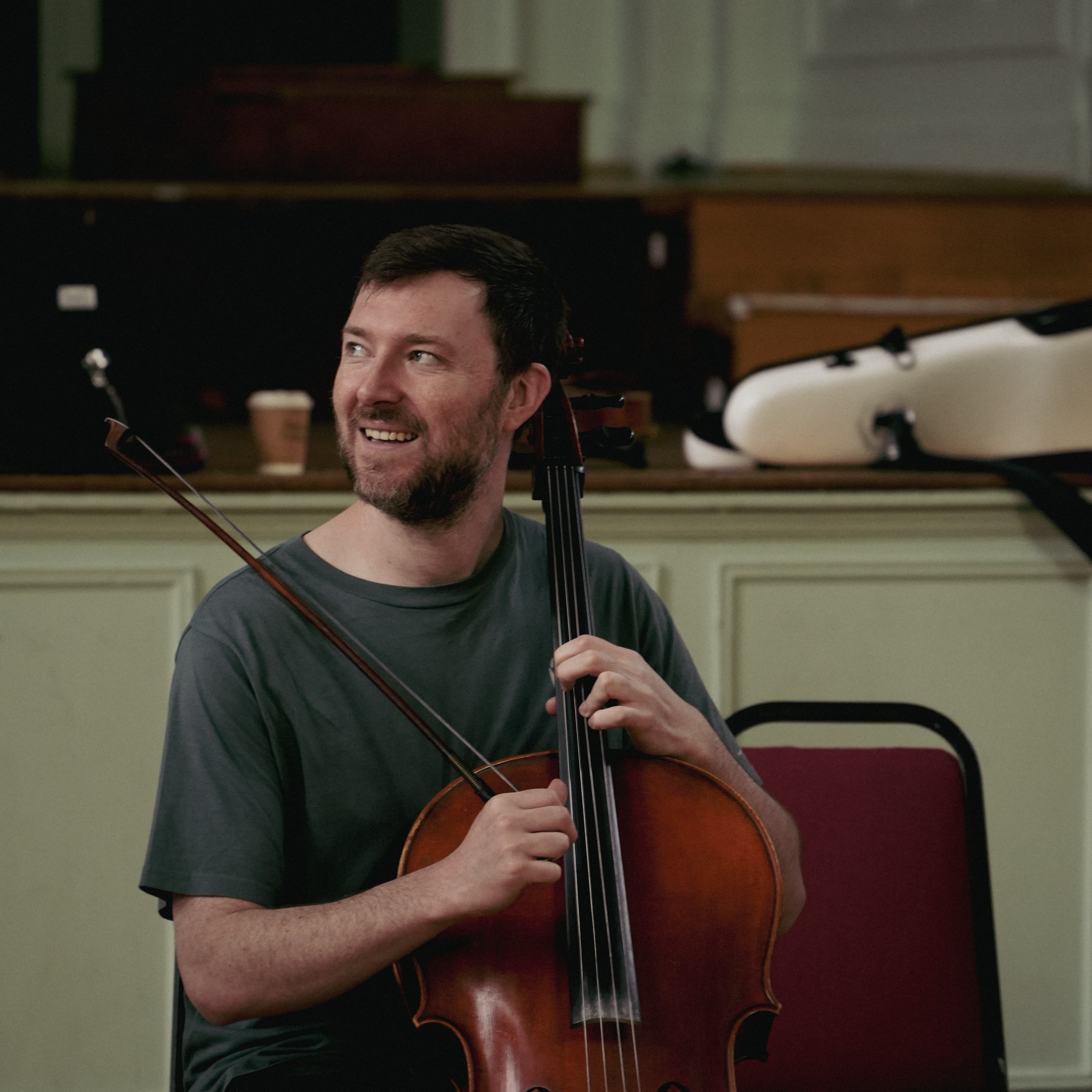 A cellist smiling and glancing aside while playing
