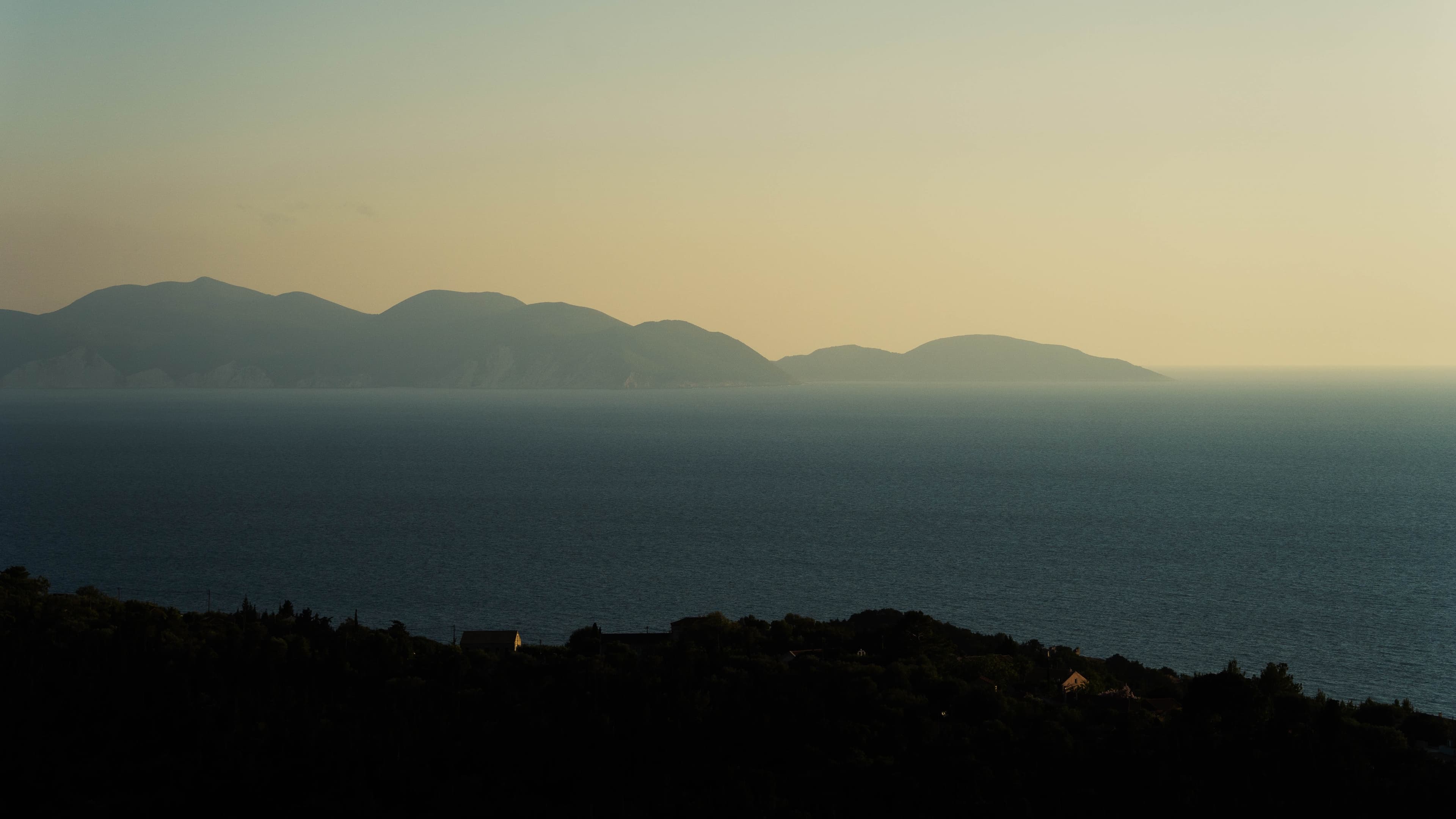 Silhouetted coastal mountains and calm sea at dusk