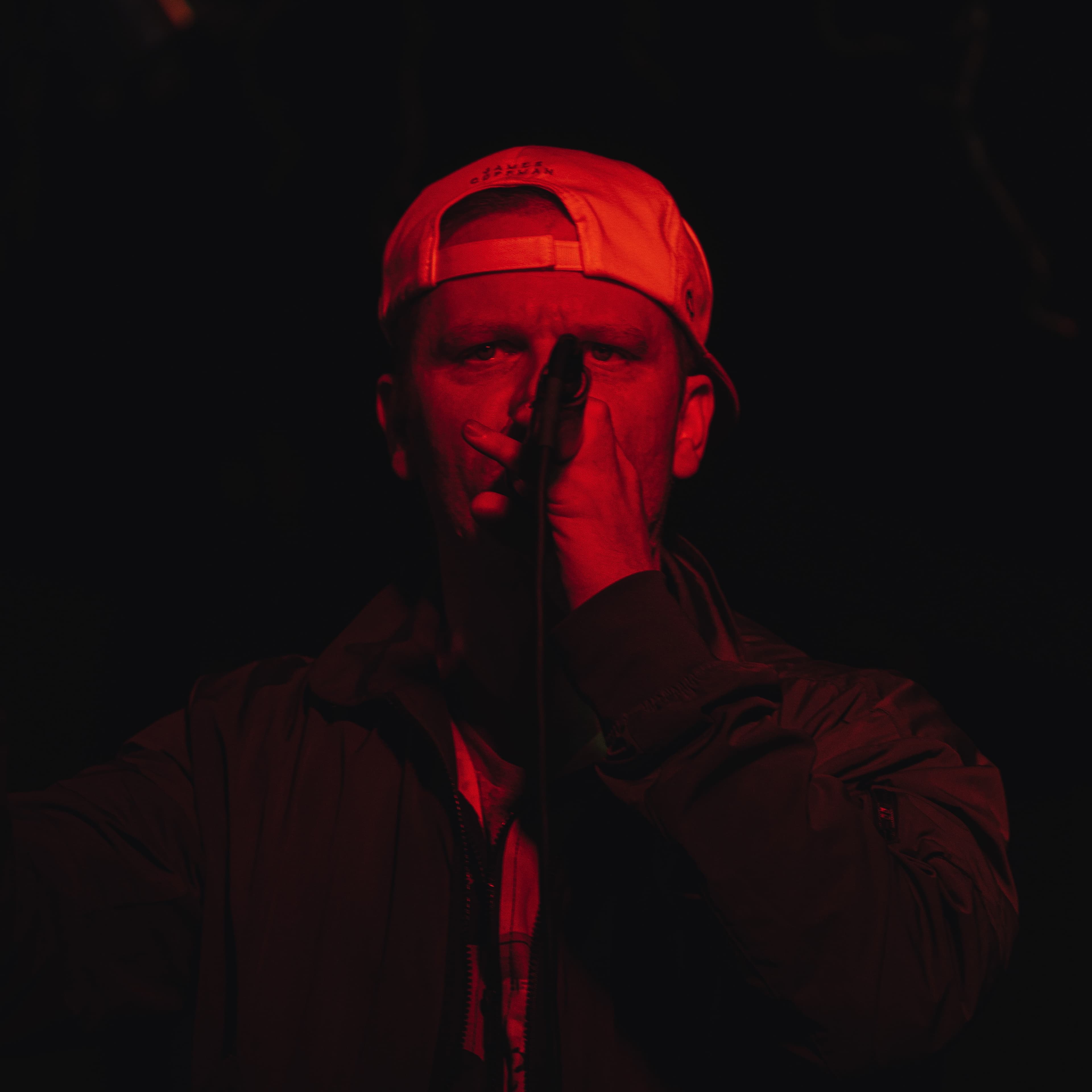 A performer holding a microphone under green and red stage lighting
