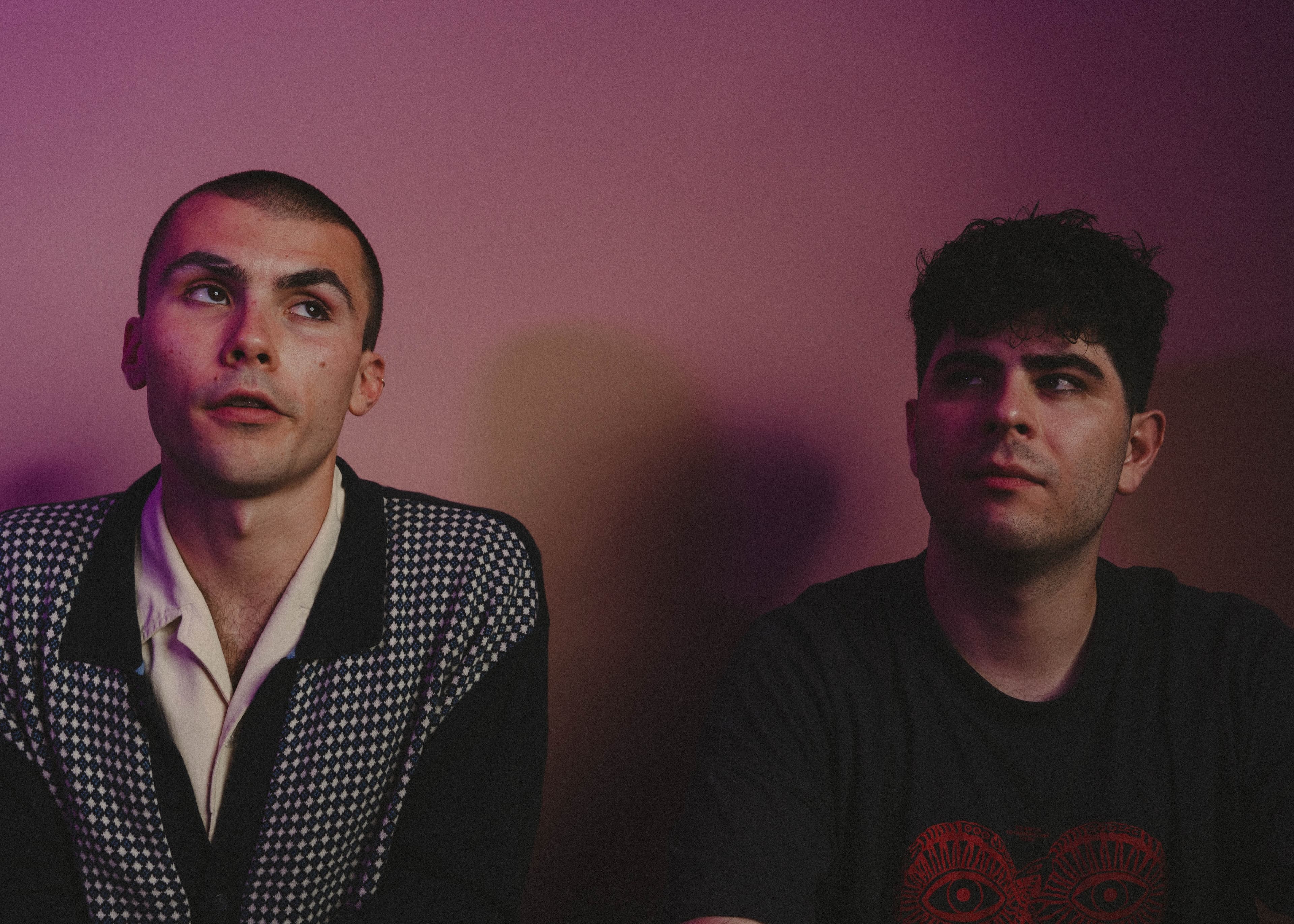 Two men looking upward under pink stage lighting