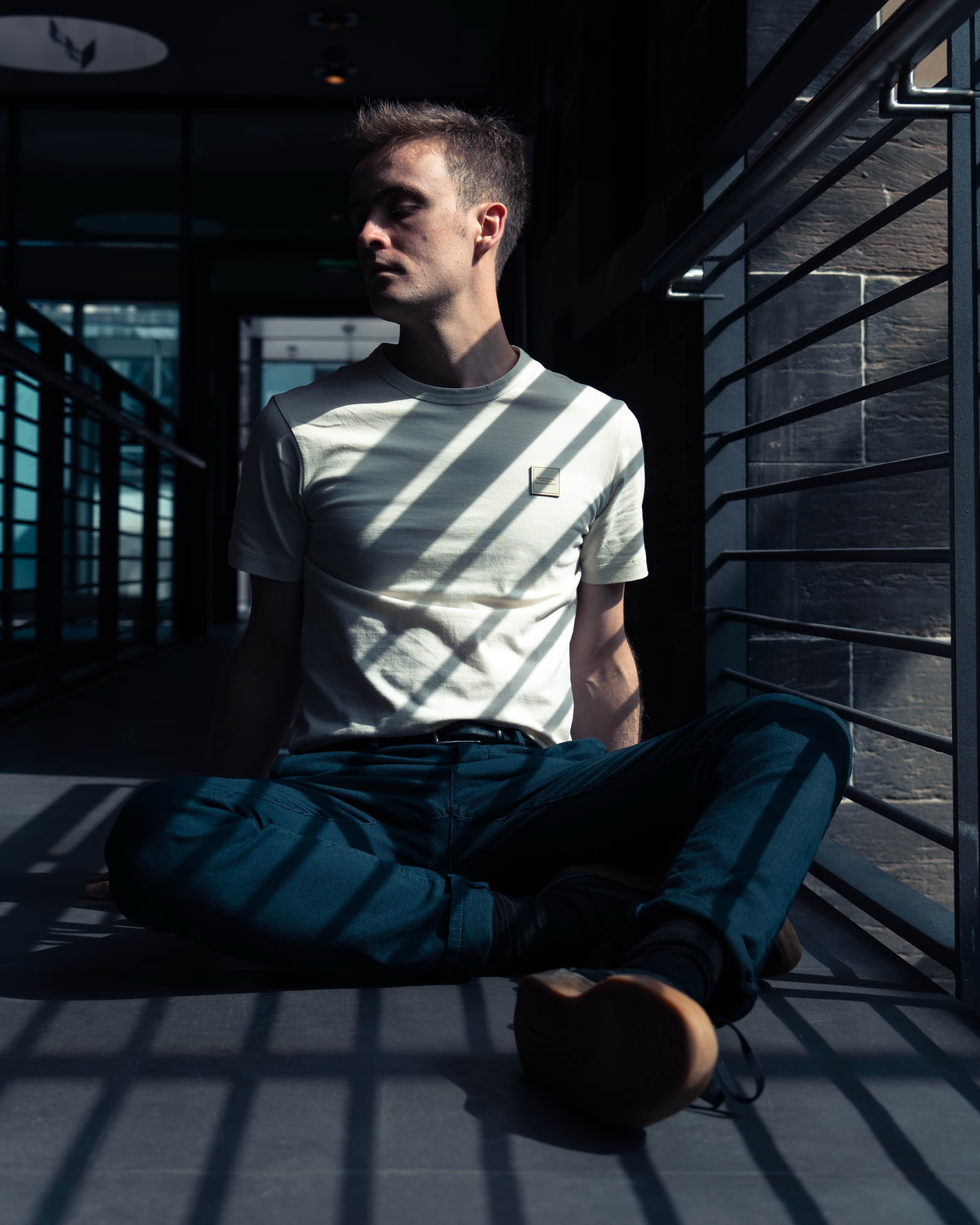 A man sitting cross-legged in bold striped shadow light
