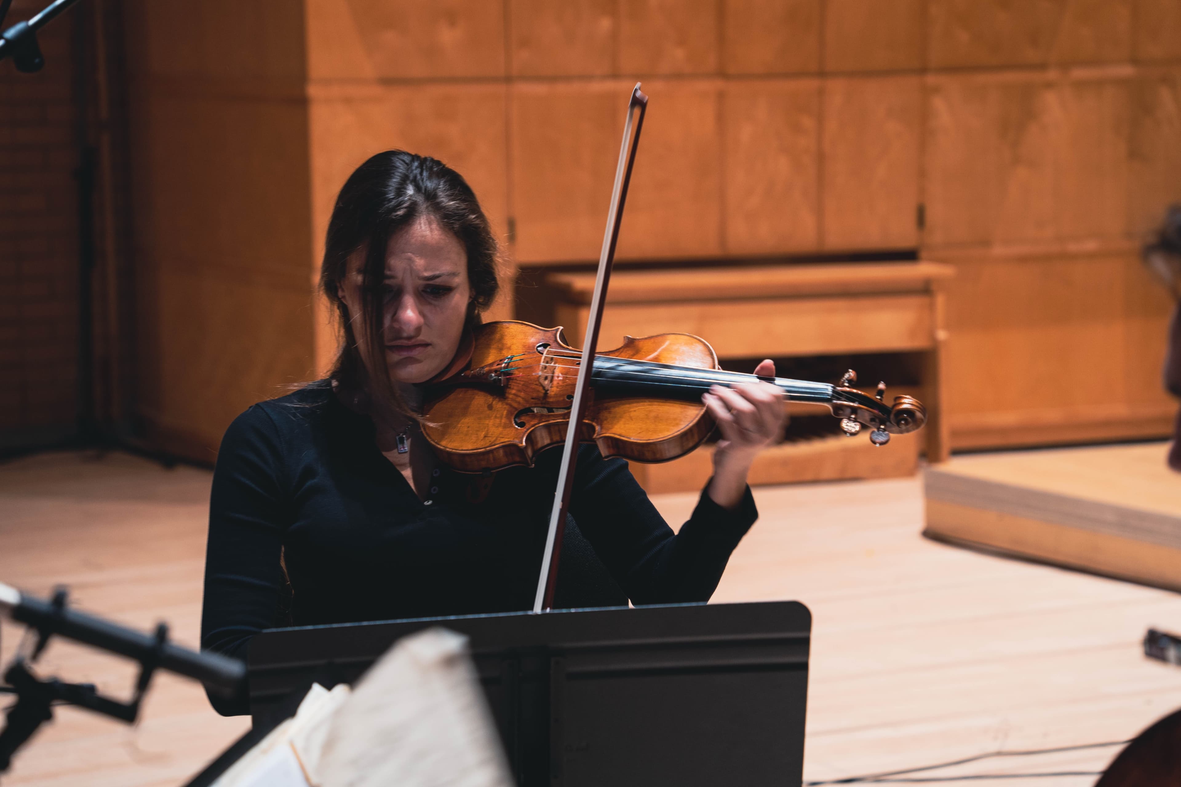 A violinist playing on stage in a warm-lit concert hall